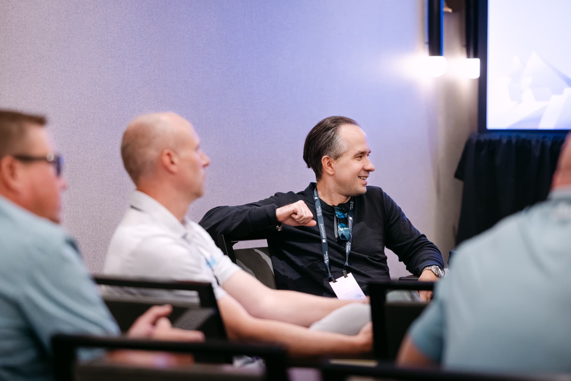 An attendee in a black sweater smiles and joins the discussion during an Operations Day session.
